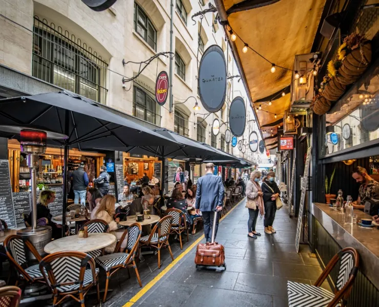 Businessman with suitcase walking through Degraves Street